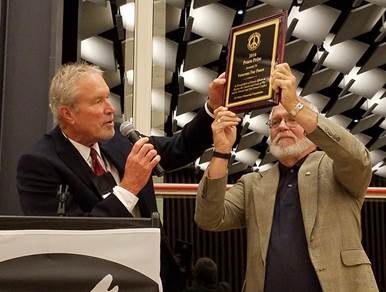 A person holding a plaque with a microphone

AI-generated content may be incorrect.